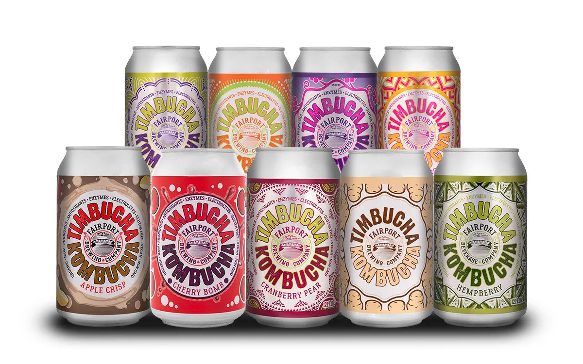Six Timbucha Kombucha cans — Peach, Apple Crisp, Ginger Root, Cherry Bomb, Purple Haze and Hempberry — reflected on a glossy surface