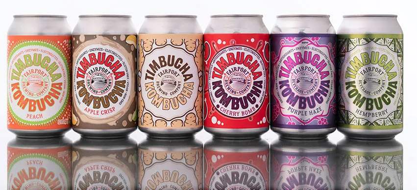 Timbucha Kombucha cans in every flavor lined up on a white surface